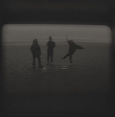 three people are standing in the water with their surfboards