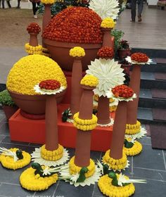 several large flower pots with yellow and white flowers in them sitting on the ground next to steps