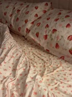 an unmade bed with strawberry print sheets and pillows