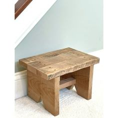 a small wooden step stool sitting in front of a stair case next to a wall