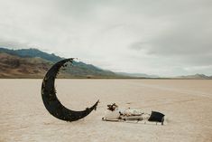 a person laying in the middle of a desert with a crescent shaped object next to them