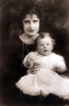 an old black and white photo of a woman holding a baby in her arms,