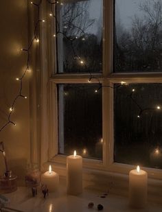 some candles are sitting on a window sill in front of the windowsill with lights