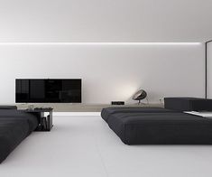 a modern living room with black couches and a flat screen tv on the wall