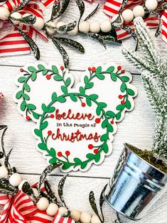 a christmas wreath with the words believe in the magic of christmas next to a potted plant