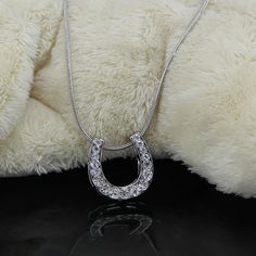 a white teddy bear with a silver necklace on it