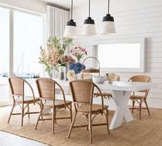 a dining room with white walls and wooden chairs