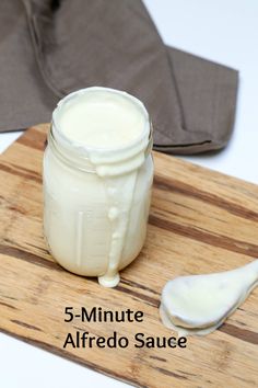 a jar of yogurt sitting on top of a cutting board next to a spoon