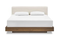 a bed with two pillows on top of it and a wooden frame in the middle