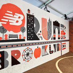 an indoor basketball court with a mural on the wall