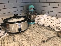 a crock pot sitting on top of a counter next to a pile of towels