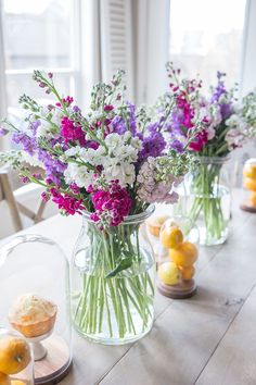 there are many vases with flowers in them on the table next to lemons