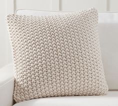 a white couch with a knitted pillow on it