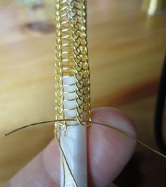 a person holding a piece of metal with some wire attached to it's end