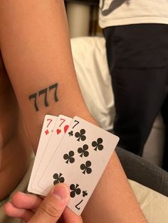 a person holding two playing cards in their left hand with hebrew symbols on the other arm