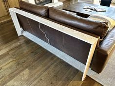 a leather couch sitting on top of a hard wood floor next to a fire place