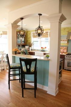 a kitchen with an island and bar stools in the center, along with two dining chairs