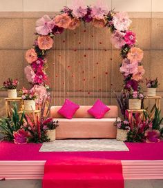 a pink and gold wedding stage decorated with flowers