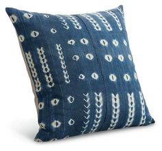 a blue and white pillow with an intricate design on the front, sitting against a white background