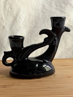 a black vase sitting on top of a wooden table