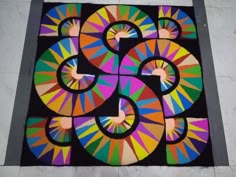 a multicolored area rug on the floor with an artistic design in the middle