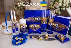 a table topped with blue and gold wedding decorations next to candles, napkins and wine glasses