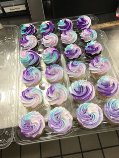 cupcakes with purple and blue frosting in a plastic container on a counter