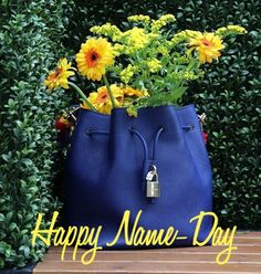 a blue purse with flowers in it sitting on a wooden table next to some bushes