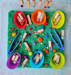 a plastic container filled with lots of different types of toy cars and toys on top of green grass