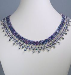 a necklace is displayed on a white mannequin with blue and purple beads hanging from it