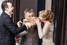 a man and woman feeding each other bread at a wedding reception in front of a microphone