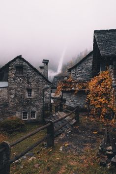 an old stone house in the mountains on a foggy day with autumn leaves and foliage