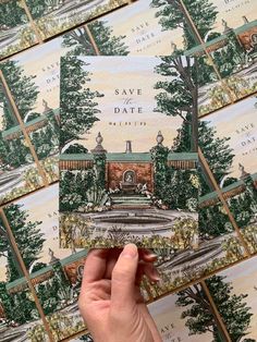 someone holding up a save the date card in front of many other greeting cards with trees on them