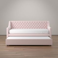 a pink couch sitting on top of a hard wood floor next to a white wall