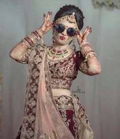 a woman in a red and gold bridal outfit with her hands on her head