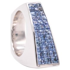 A Geometric cocktail ring with Ceylon Blue Sapphires. An aerodynamic bold piece made in Italy, with an asymmetric shape. It was crafted in solid white gold of 18 karats, with highly polished surfaces. Is set on top with calibrated invisible settings of 36 French squared step cuts of natural vivid Ceylon blue sapphires, with a total weight of 2.52 carats. Have a total weight of 22.8 grams and the actual size is 6, sizable. The top view measures are 9 mm by 23 mm. Stamped, with the Italian assay c Ceylon Blue Sapphire, Geometric Ring, Geometric Jewelry, Top View, Cocktail Ring, Cocktail Rings, Blue Sapphire, Jewelry Box, Jewelry Watches