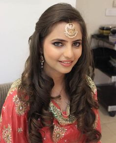 a woman with long hair wearing a red dress and gold jewelry on her head, smiling at the camera