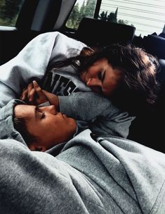 two children sleeping in the back of a car with their heads on each other's shoulders