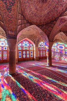 the inside of an ornate building with many windows and colorful lights on it's walls