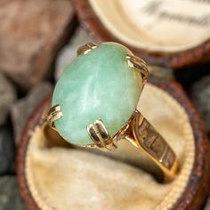 This lovely jade solitaire ring is 4-prong set with an oval cabochon cut jadeite jade that sits above a pierced scrolling gallery. The ring is crafted in 10k yellow gold. Formal Oval Jade Emerald Ring, Oval Jade Rings Hallmarked, Classic Oval Chrysoprase Ring, Elegant Oval Chrysoprase Rings, Vintage Oval Jade Emerald Ring, Vintage Oval Jade Rings, Jade Rings With Polished Finish, Oval Cabochon, Jade Rings With Polished Finish In Oval Cabochon Shape, Jade Oval Cabochon Rings With Polished Finish