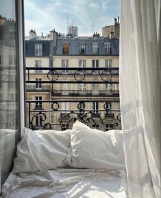 a bed sitting in front of a window next to a white blanket and pillow on top of a bed