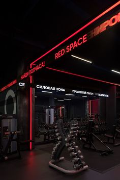 an empty gym with red neon lights on the ceiling and treadmills in the foreground