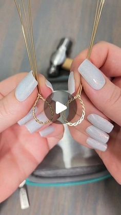 two hands holding some kind of necklace with long, thin nails on top of it