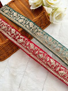 two red and green ribbons sitting on top of a basket next to white flowers in a vase