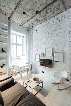 a living room with white brick walls and wooden flooring is furnished with modern furniture