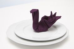 two white plates topped with purple napkins sitting on top of each other next to one another