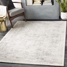 a white rug with an ornate design on the floor next to a chair and bookshelf