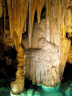 the inside of a cave with green water and large stalate formations hanging from the ceiling