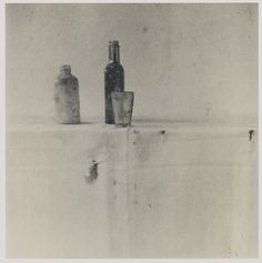 two bottles and a shot glass are sitting on a table in front of a wall