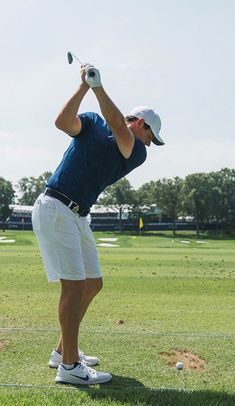 a man in blue shirt and white shorts playing golf